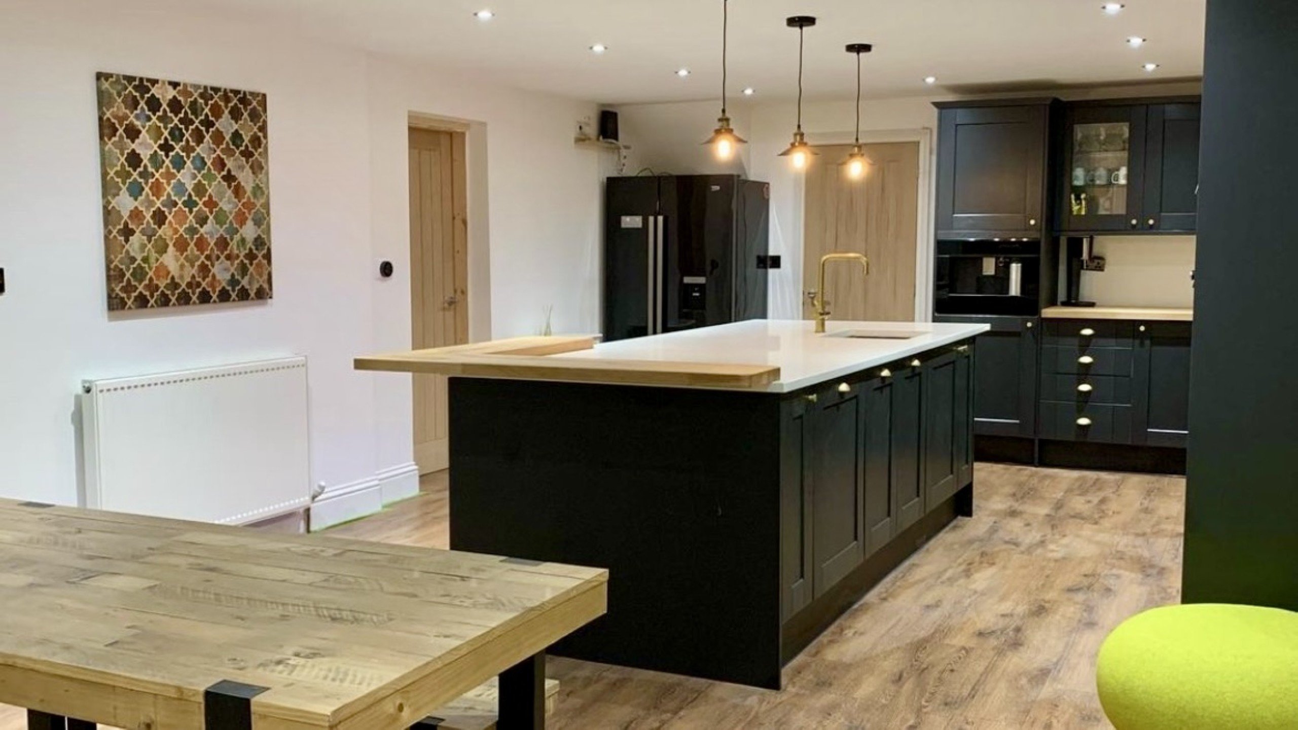 Modern kitchen with sleek island, rustic dining table, and stylish decor for elegant gatherings.